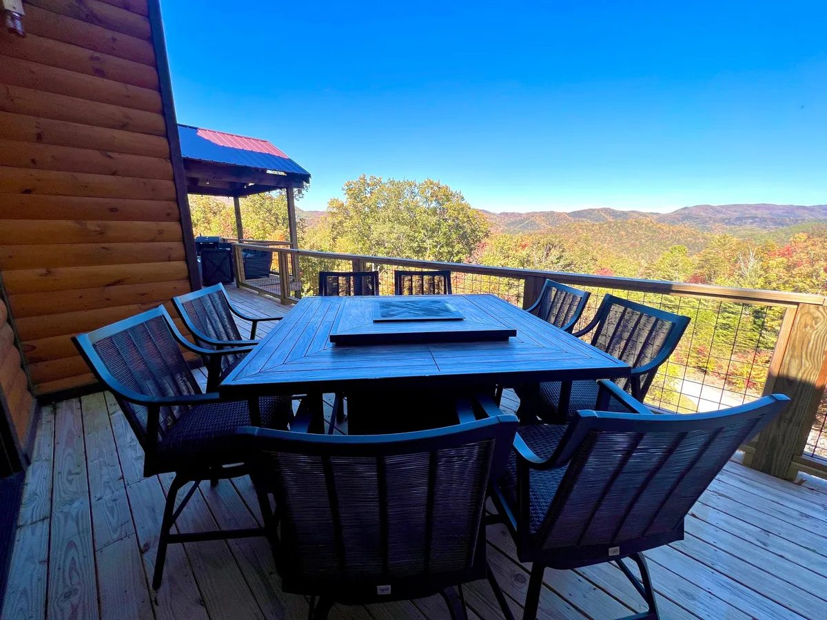 A spacious wooden deck with a dining table and chairs overlooks sweeping mountain views. The setting is ideal for outdoor meals, group discussions, or informal team gatherings, connecting guests with nature while fostering conversation.