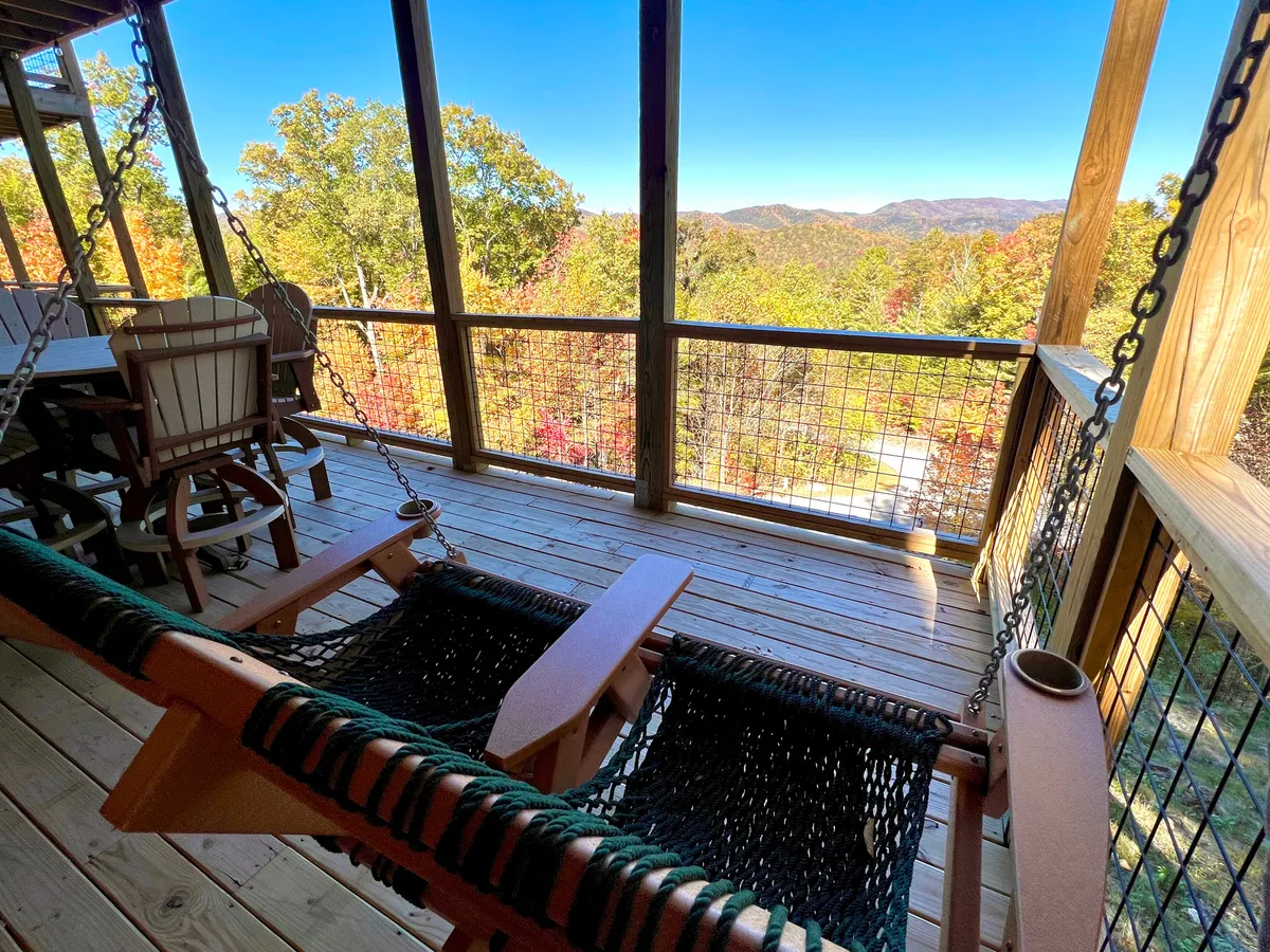 An inviting exterior space showcasing swing chairs and a dining table positioned to take in a sweeping mountain view. The autumnal colors and expansive vista create an atmosphere of serenity and luxury, ideal for enjoying morning coffee, sunset drinks, or stargazing with loved ones.