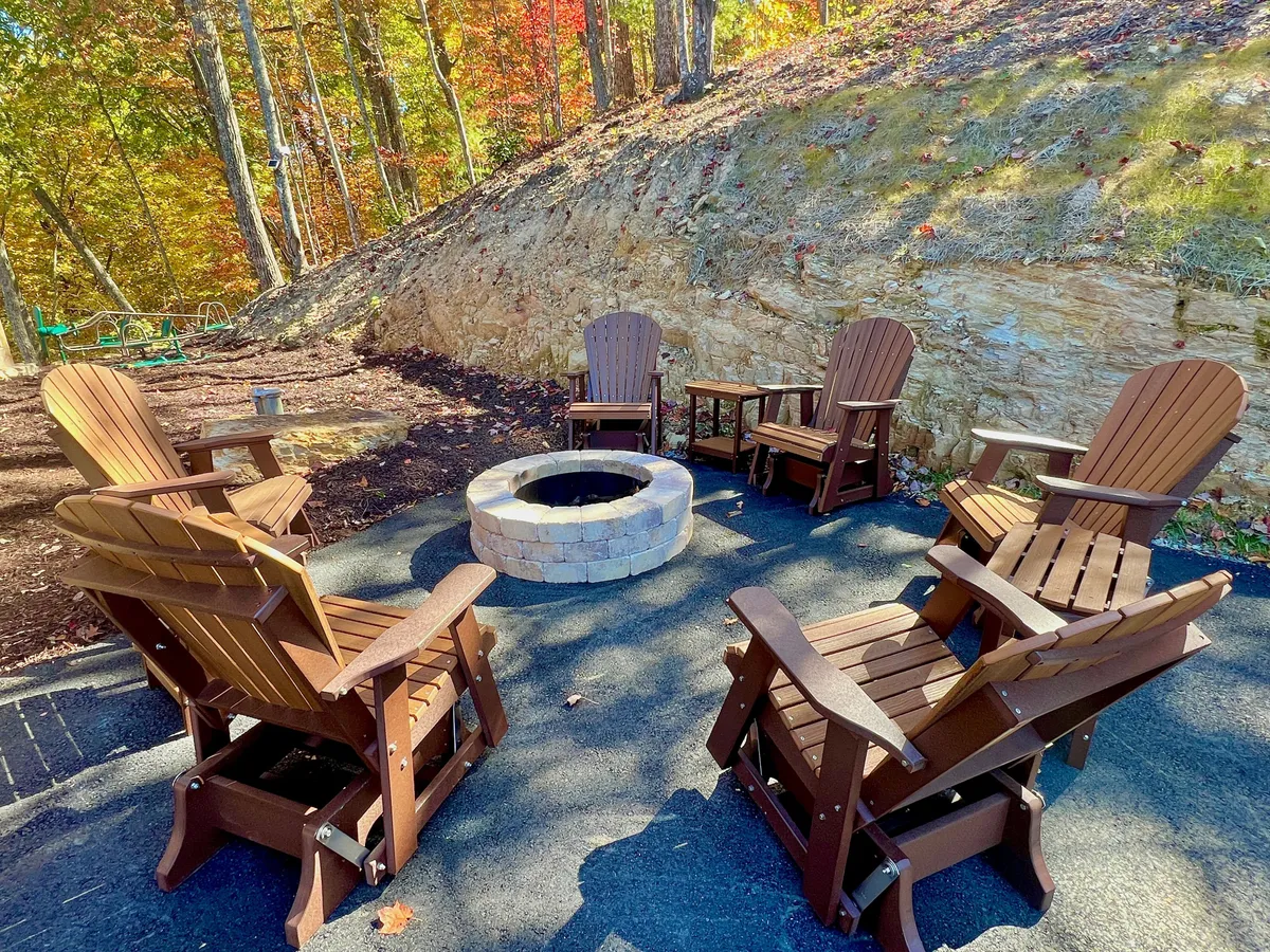 A cozy fire pit area features Adirondack chairs encircled by trees, offering an inviting space for storytelling, evening relaxation, and team bonding under the stars. The natural surroundings further emphasize the lodge's immersive outdoor experience.