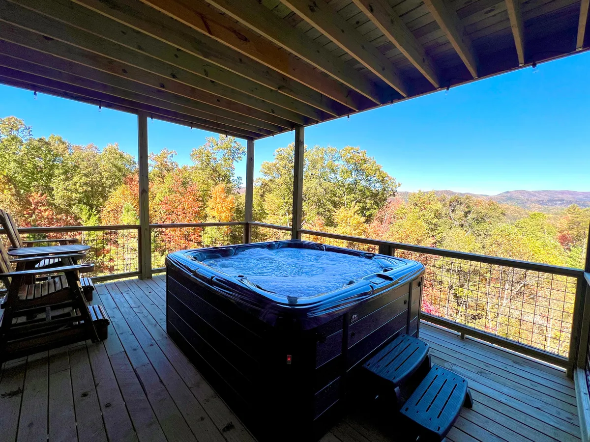 This image features a hot tub on a wooden deck, with rocking chairs and a scenic mountain view. The tranquil setting is perfect for relaxing in the evening, socializing with friends or family, and appreciating the surrounding natural beauty.