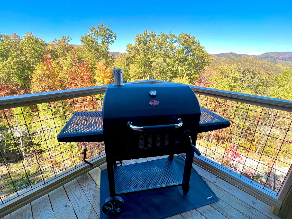 A cheerful outdoor area featuring a grill and seating, set against a mountain backdrop with vivid autumn foliage. This space invites guests to savor barbecues, share stories over meals, and watch sunsets, all while immersed in the colors of the Smoky Mountains.